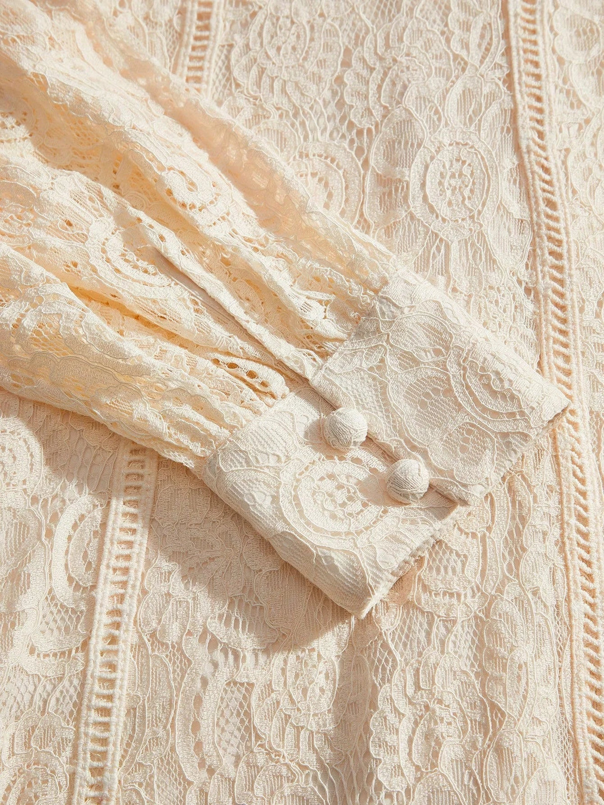 This delicate cream lace dress features intricate floral patterns and a soft, flowing fit that exudes elegance. The buttoned.
