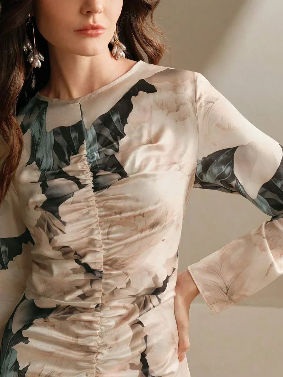 This elegant long-sleeve dress features a delicate floral print in soft beige and muted greens, beautifully accentuating its.