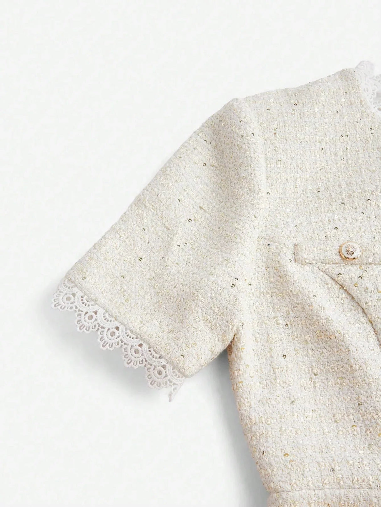 This elegant cream dress features a textured fabric adorned with subtle golden flecks, creating a luxurious visual appeal..