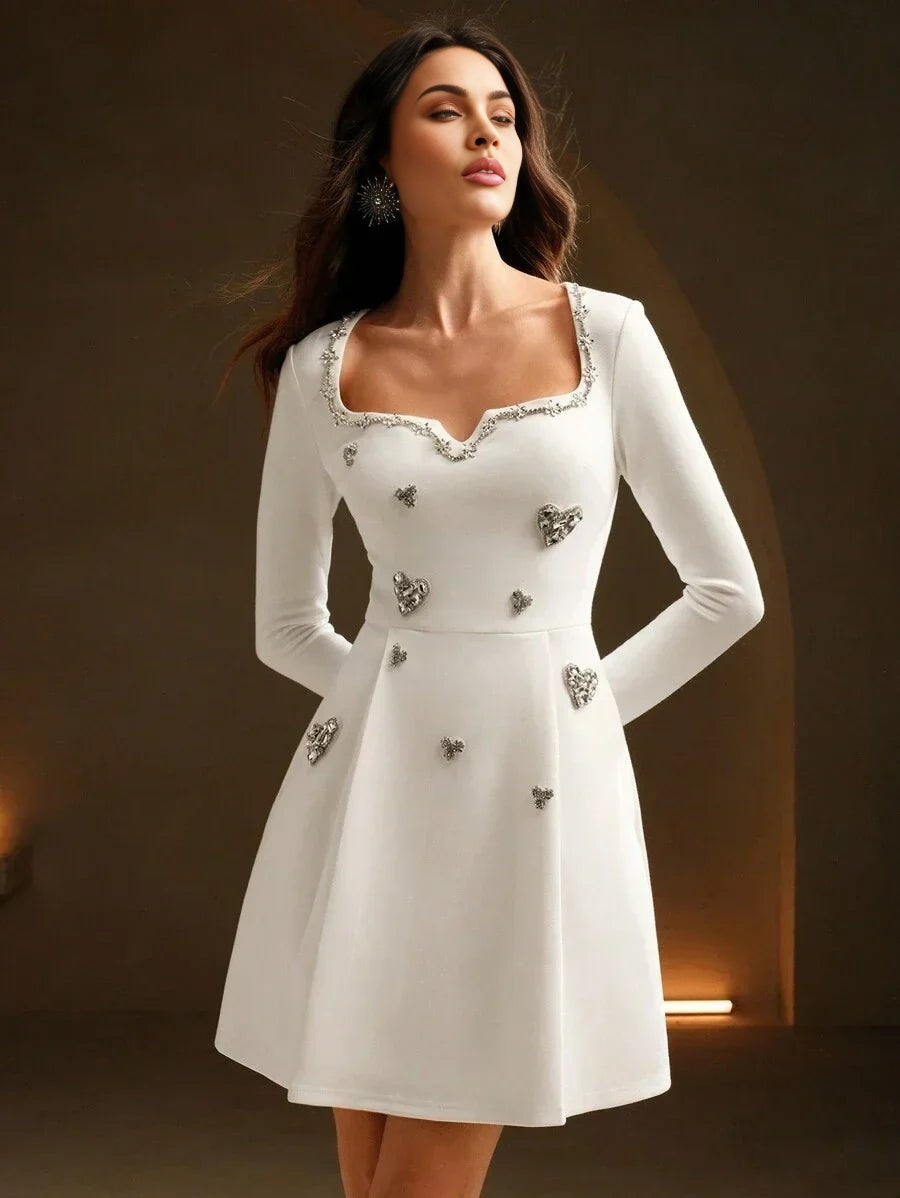 This elegant white dress features a flattering fitted bodice and a playful flared skirt, adorned with sparkling heart-shaped.