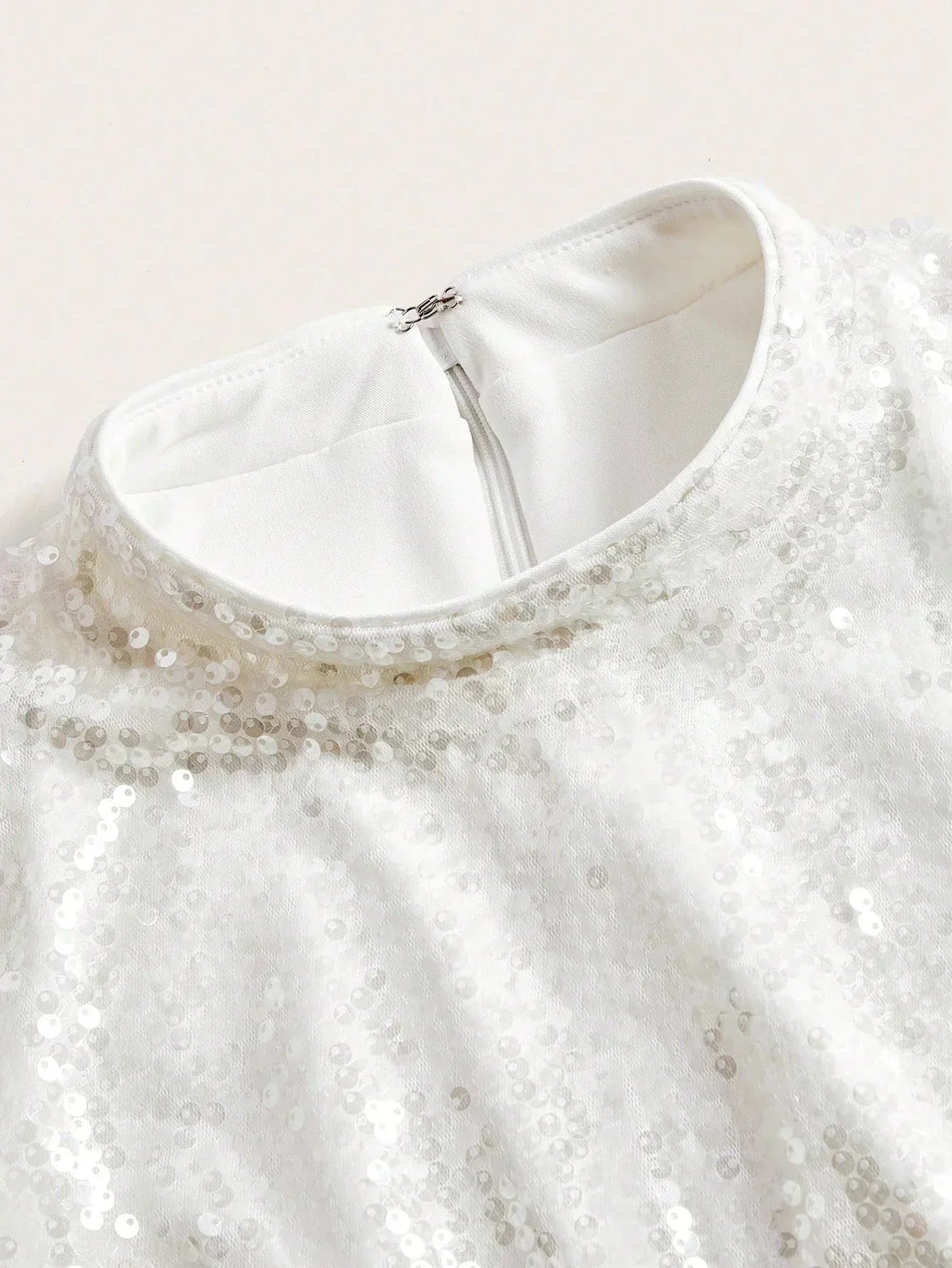 This elegant white dress features a sparkling sequin embellishment that adds a touch of glam, perfect for special occasions..