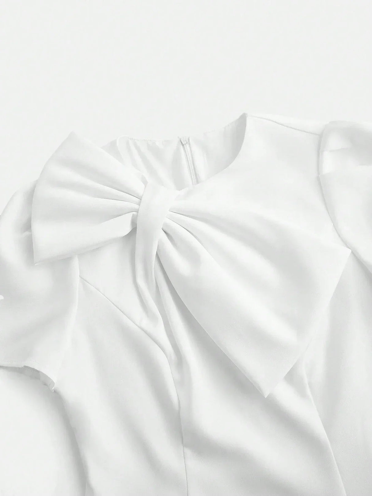 This elegant white dress features a sophisticated bow detail at the neckline, crafted from lightweight, flowing fabric that.