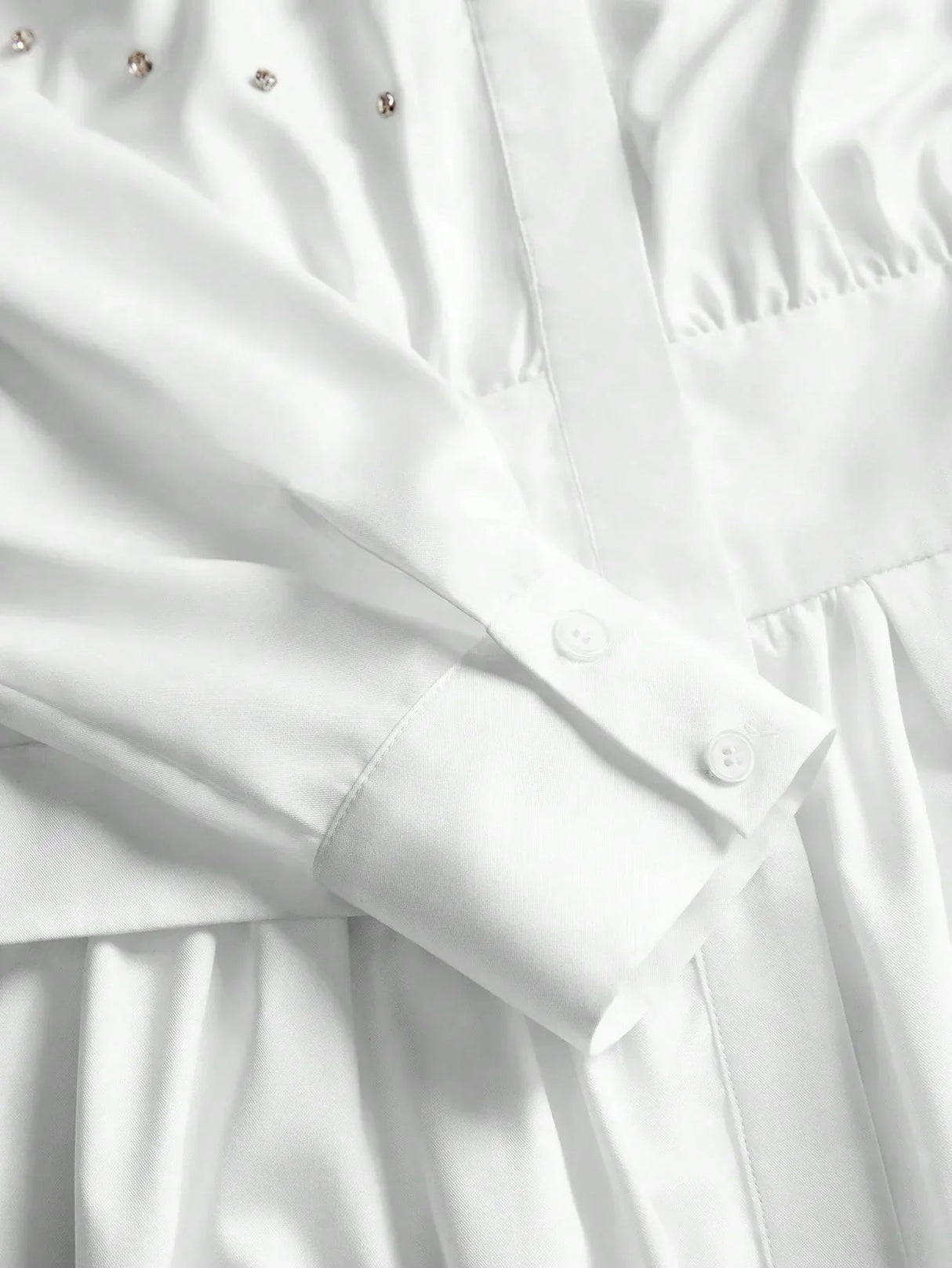 This elegant white dress features a sophisticated button-up design with delicate detailing along the bodice, complemented by.