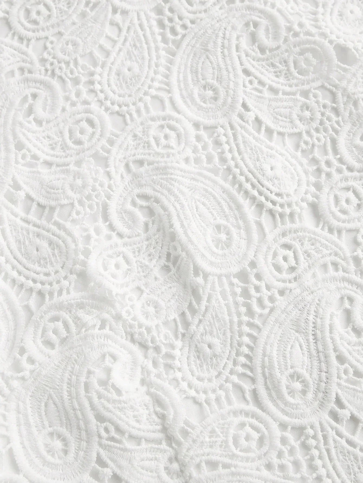 Delicate white lace fabric features an intricate paisley pattern, creating an elegant and airy look perfect for warm-weather.