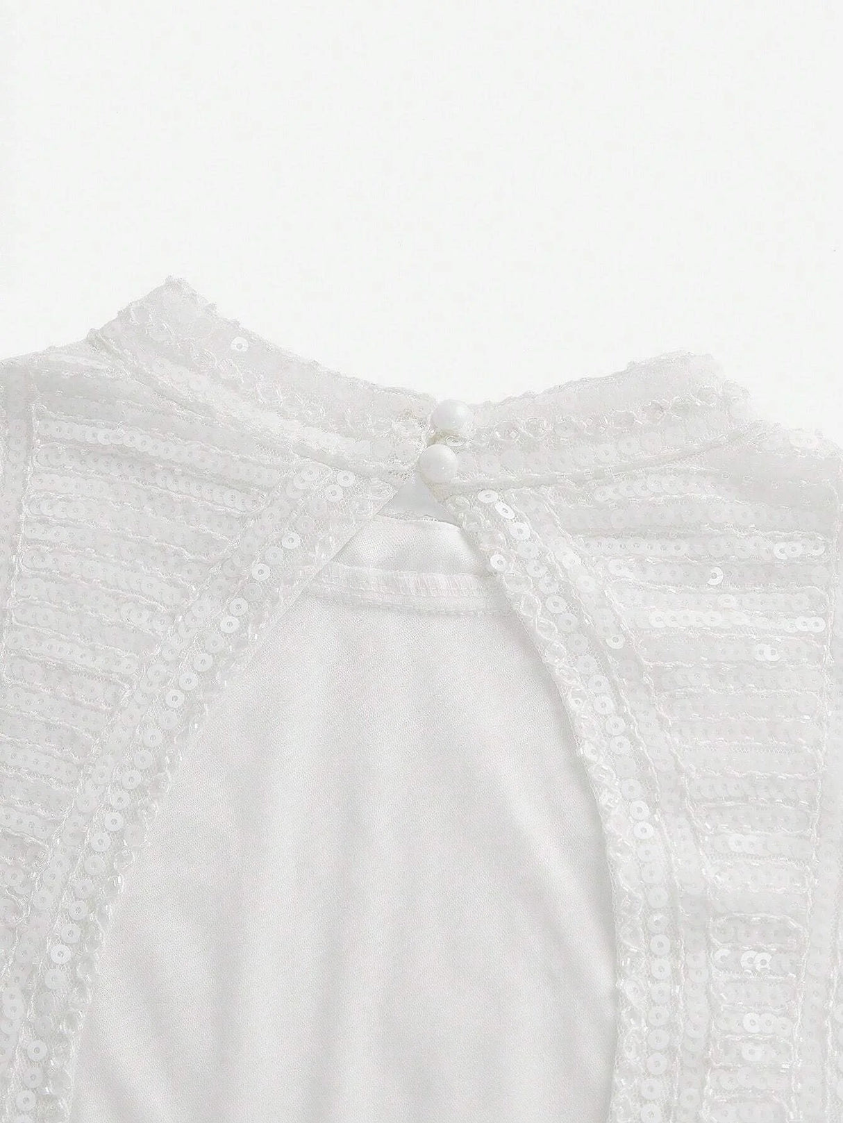 This elegant white dress features a delicate, sequined bodice that shimmers softly in the light, complemented by a smooth.