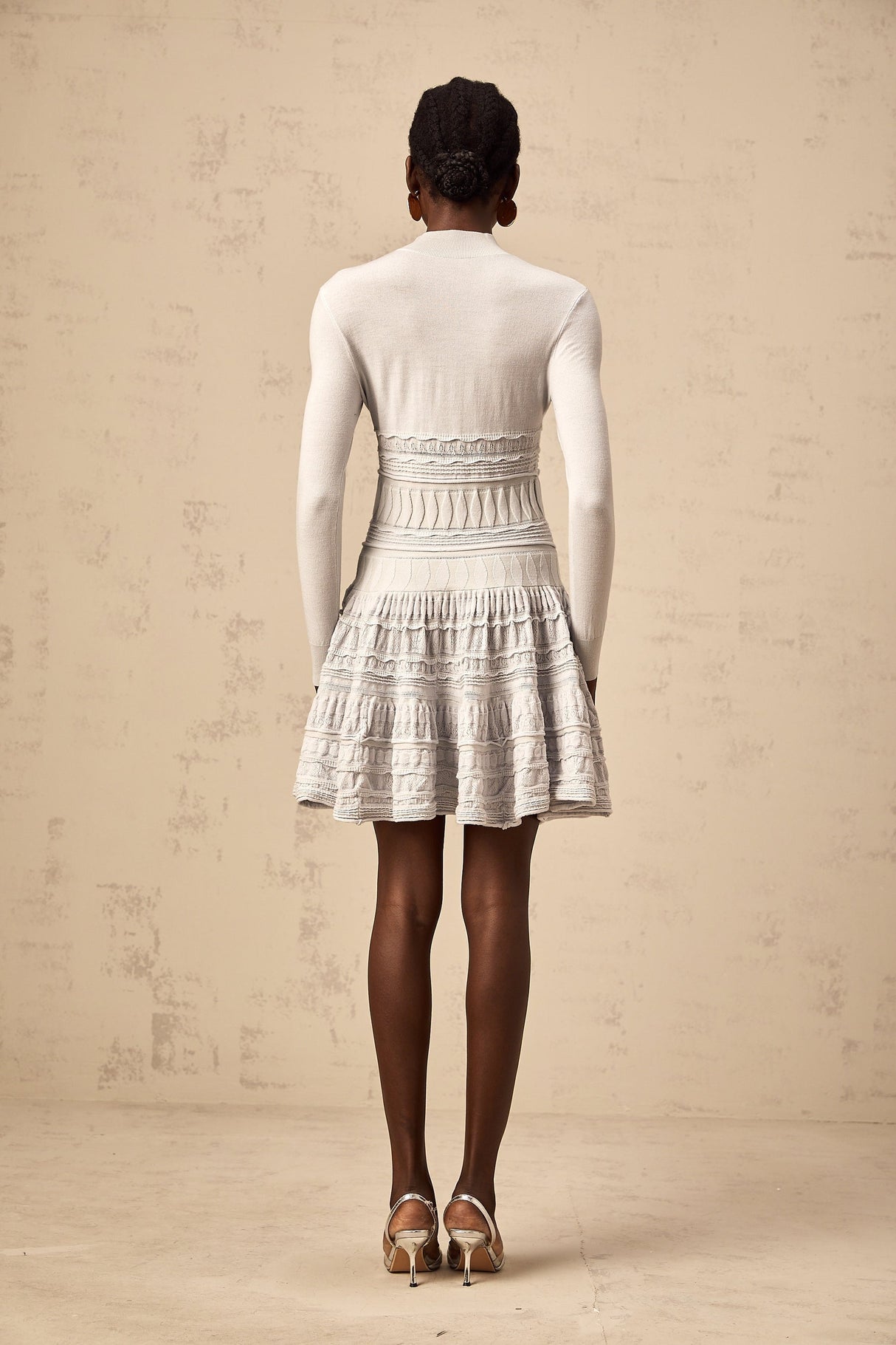 Woman wearing a short grey dress with ruffle details and ribbed texture