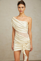 A beige asymmetric mini dress with lace panel details and a neutral color scheme