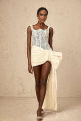 A beige mini dress with floral lace pattern featuring a bow accent and pencil skirt silhouette