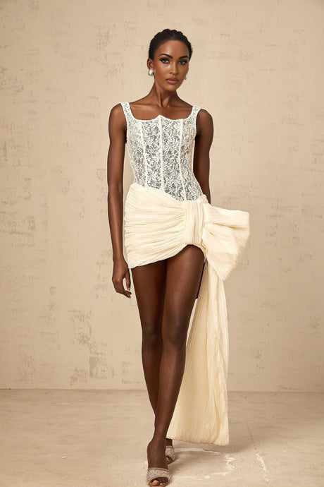 A beige mini dress with floral lace pattern featuring a bow accent and pencil skirt silhouette