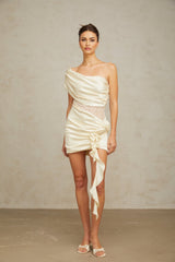 A beige mini dress with lace panels and an asymmetric hemline featuring a sleeveless design and neutral tones