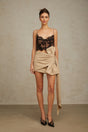 A beige mini skirt with ruched detailing and a bow accent at the waistline featuring a fanny pack style design
