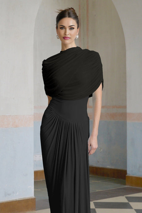 A black asymmetric maxi dress with pleated details and a flowing silhouette worn by a model standing against a plain background