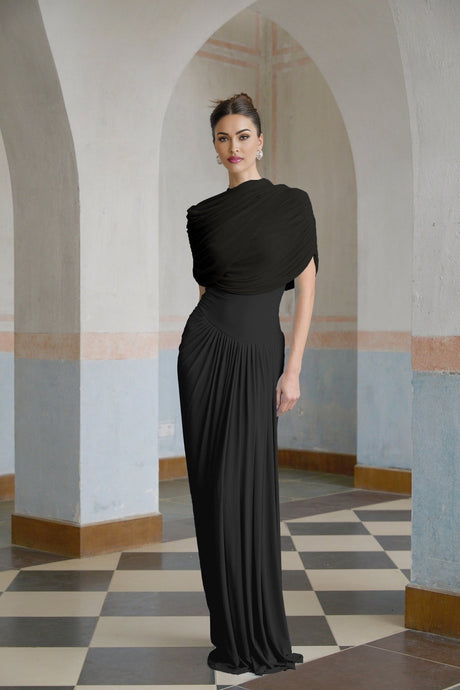 A black asymmetric maxi dress with pleated details worn by a female model standing against a plain background