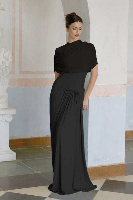 A black asymmetric maxi dress with pleats named Catherine worn by a model standing against a plain background