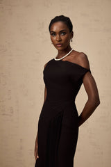 A black asymmetric midi dress with draped detailing worn by a model standing against a plain background