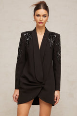 A black blazer dress adorned with sequins and embellishments featuring a tailored silhouette and shimmering details