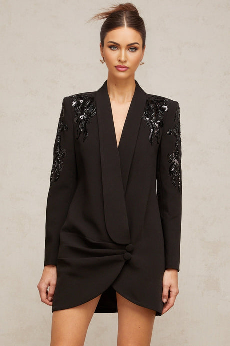 A black blazer dress adorned with sequins and embellishments featuring a tailored silhouette and shimmering details
