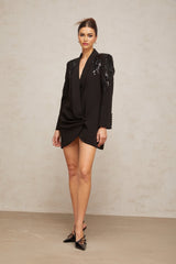 A black blazer dress adorned with sequins and embellishments featuring a tailored silhouette and sparkly detailing