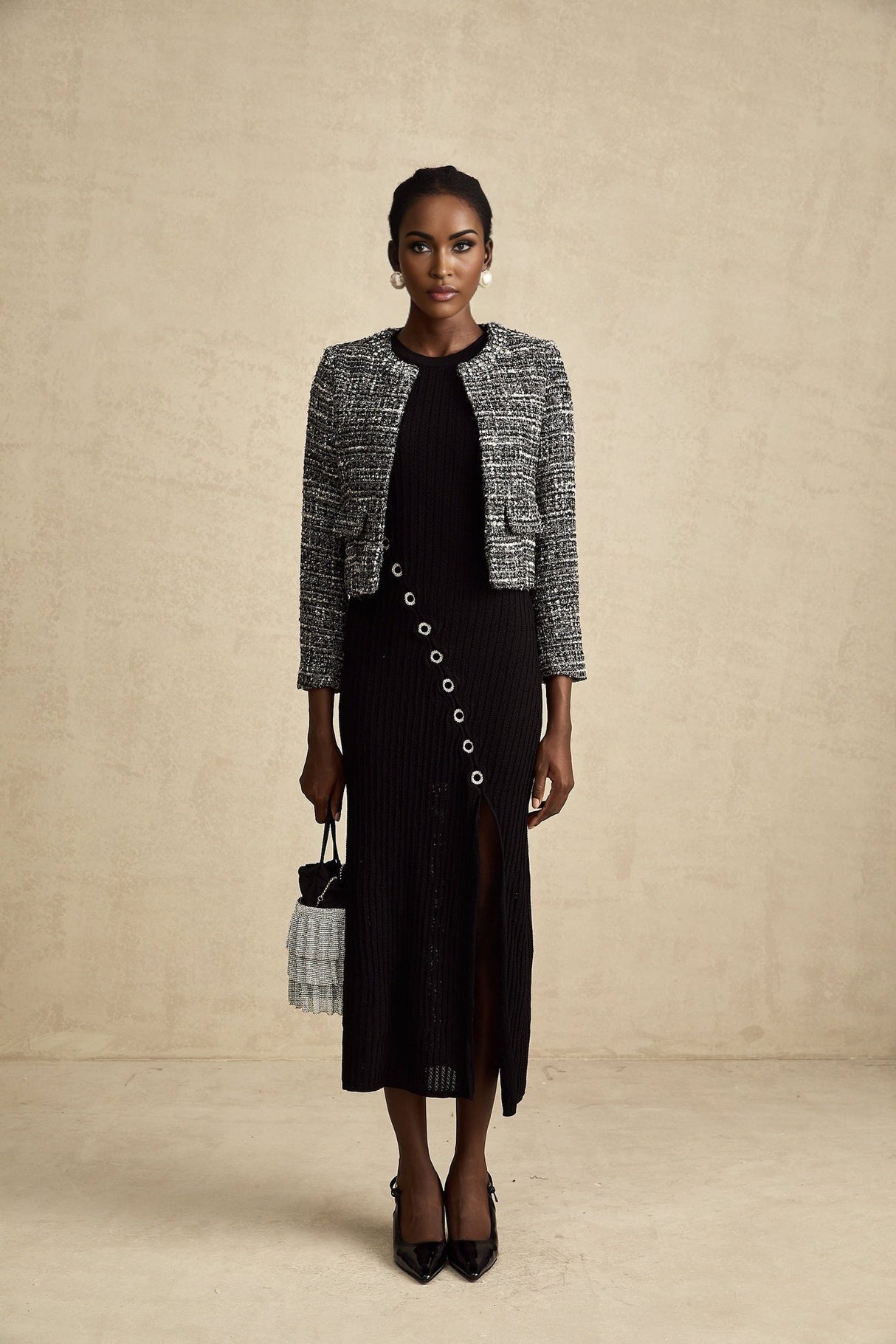 A black bouclé tweed jacket named Éloïse hanging on a clothing rack or mannequin showing its textured fabric and classic design