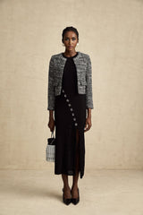 A black bouclé tweed jacket named Éloïse hanging on a clothing rack or mannequin showing its textured fabric and classic design