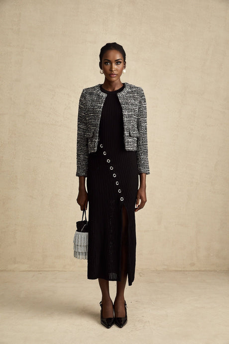 A black bouclé tweed jacket named Éloïse hanging on a clothing rack or mannequin showing its textured fabric and classic design