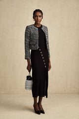 A black bouclé tweed jacket with a classic design featuring textured fabric and a tailored silhouette