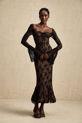 A black flared maxi dress with lace details and a Marlene style silhouette on a plain background