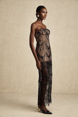 A black floor length dress with a corset bodice covered in sequins and a sheer mesh skirt