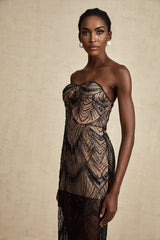 A black floor length dress with a corset bodice covered in sequins and a sheer mesh skirt