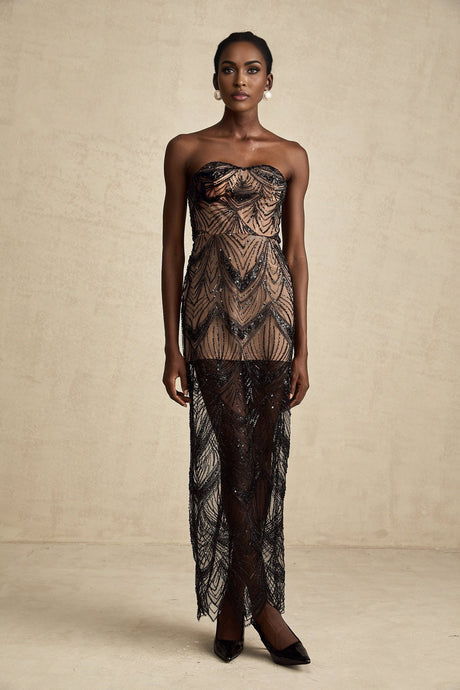 A black floor length dress with a corset bodice covered in shimmering sequins and a flowing mesh skirt