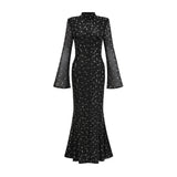 A black floor length maxi dress with sheer elements and embellishments worn by a female model