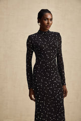 A black floor length maxi dress with sheer fabric and decorative embellishments worn by a model