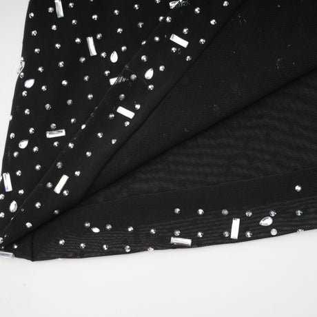 A black floor length maxi dress with sheer fabric and embellished details worn by a model