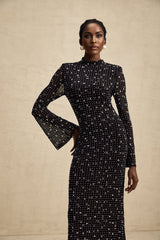 A black floor length maxi dress with sheer fabric and embellished details worn by a model