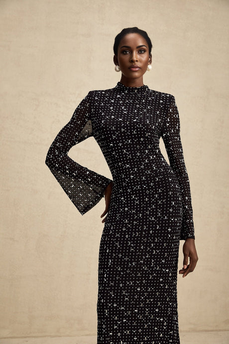 A black floor length maxi dress with sheer fabric and embellished details worn by a model