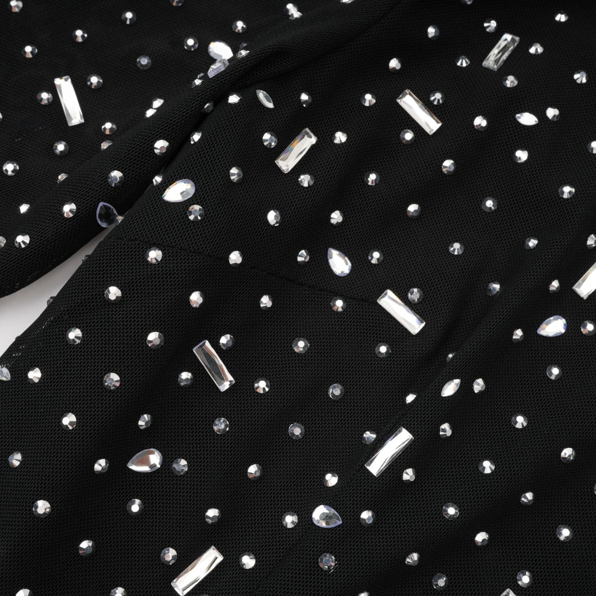 A black floor length maxi dress with sheer panels and embellished details worn by a model against a plain background