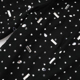 A black floor length maxi dress with sheer panels and embellished details worn by a model against a plain background