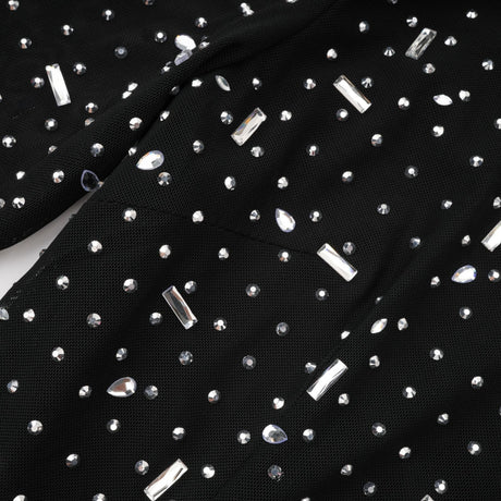 A black floor length maxi dress with sheer panels and embellished details worn by a model against a plain background