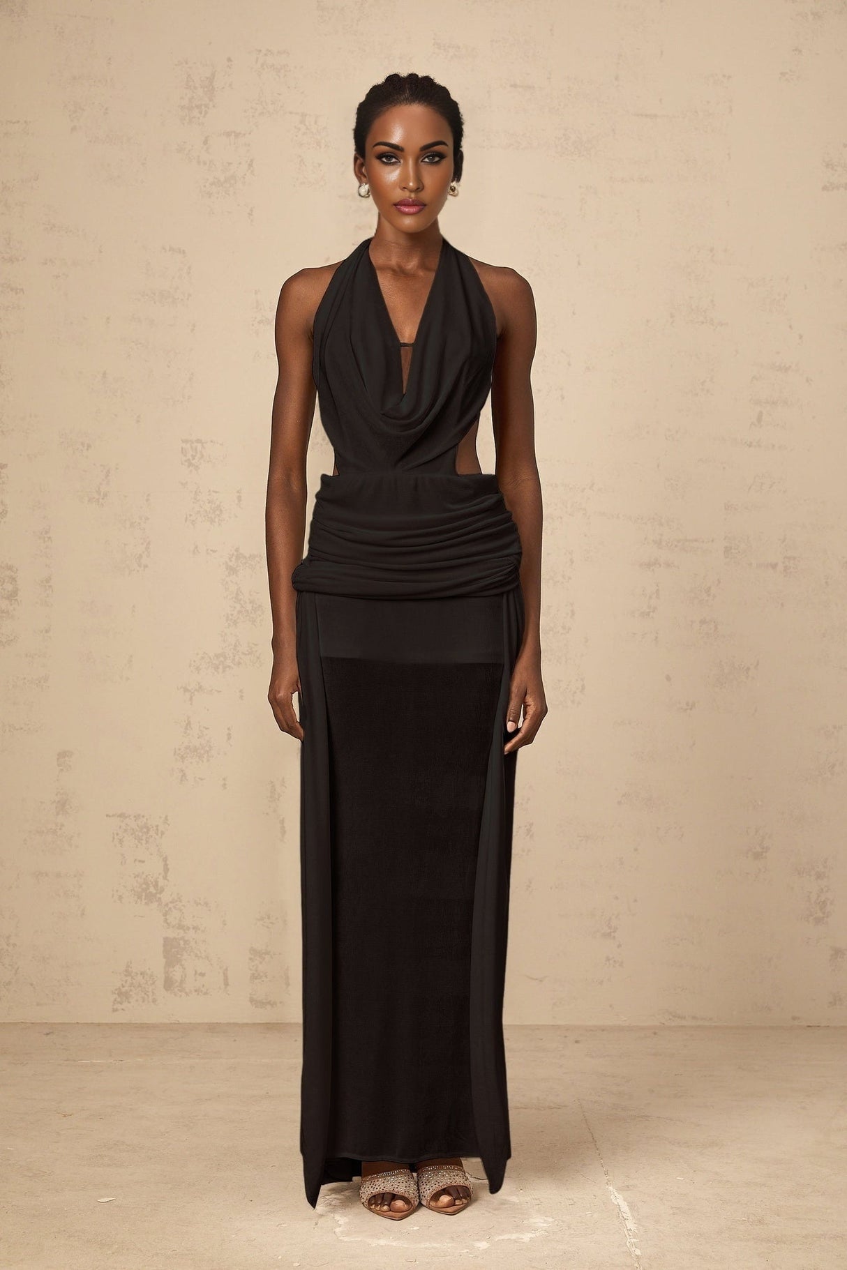 A black floorlength maxi dress with a halter neckline and open back design worn by a model