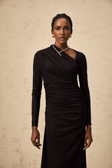 A black floorlength tulle dress with an asymmetric cut and cutout details worn by a model standing against a plain background