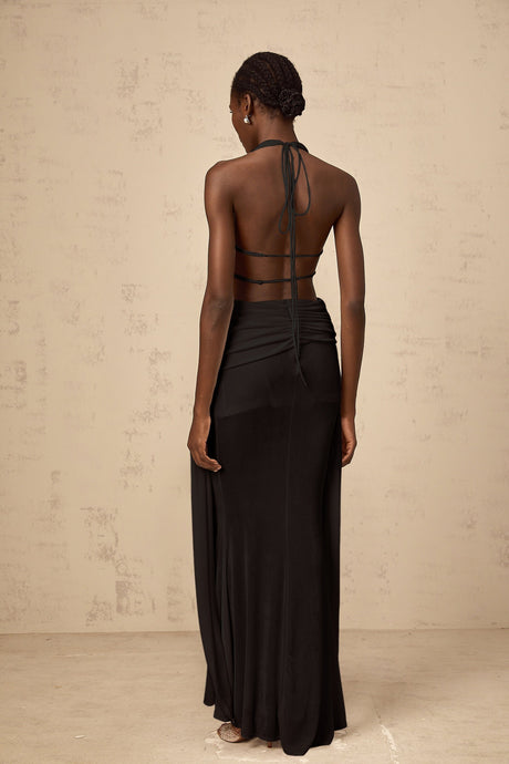 A black halterneck maxi dress with a backless design featuring a long flowing skirt and sleek silhouette