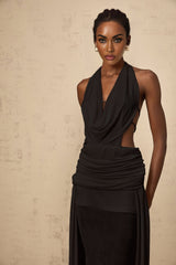 A black halterneck maxi dress with a backless design featuring a long flowing skirt and sleeveless style