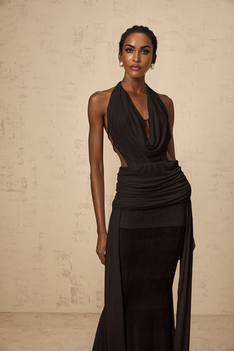 A black halterneck maxi dress with a backless design hanging on display