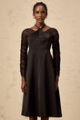 A black halterneck midi dress with panel detailing worn by a model against a plain background