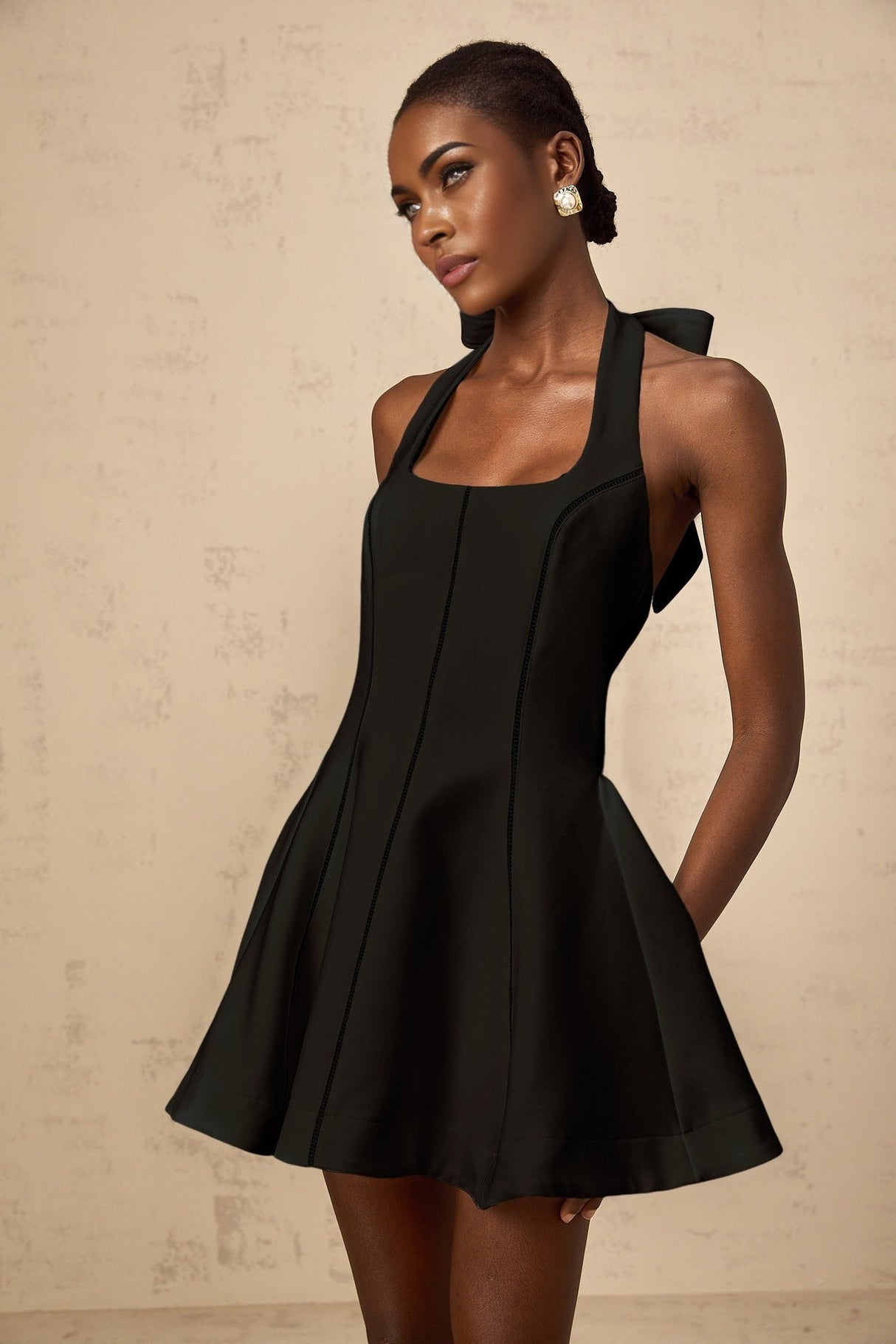 A black halterneck mini dress with a bow detail featuring a sleek and stylish design by Quirine