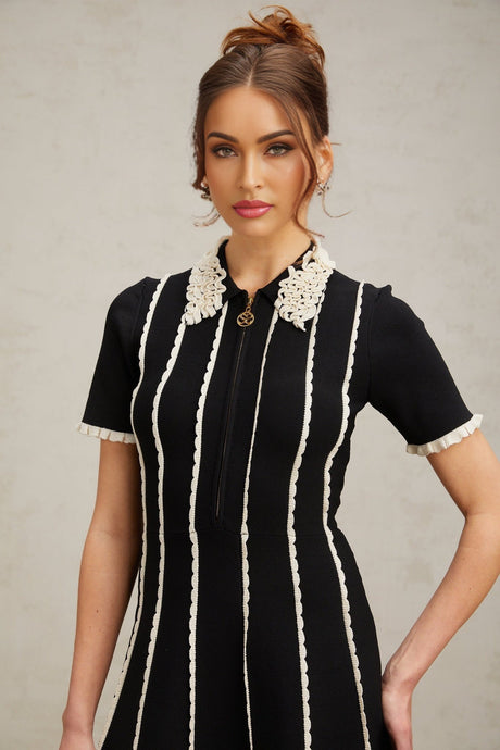 A black knit mini dress with vertical stripes and ruffle trim details called Zazie