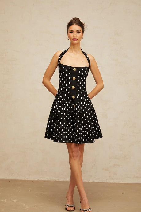 A black knit mini dress with white polka dots featuring short sleeves and a fitted silhouette called Sandrine