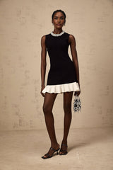 A black knitted mini dress with ruffled details and faux pearl embellishments