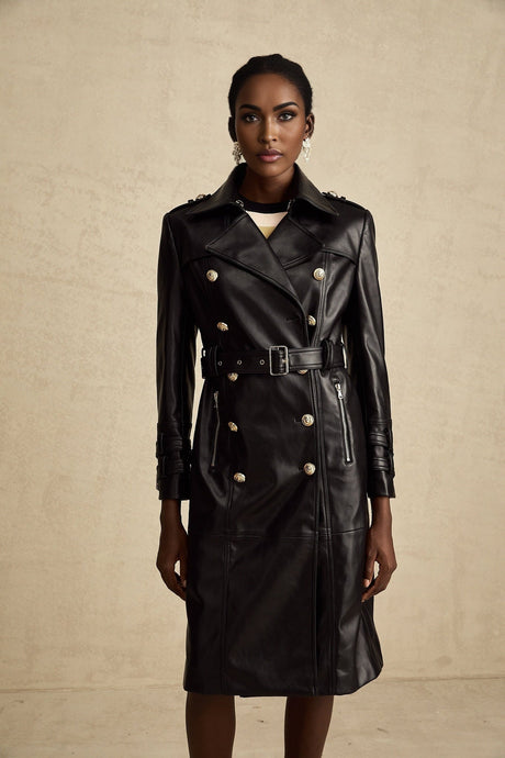 A black leather coat with double breasted closure and a belt cinching the waist worn by a model