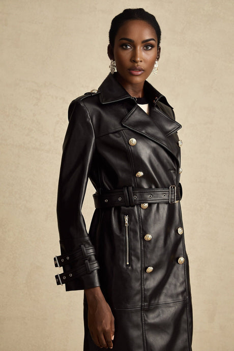 A black leather coat with double breasted front and belted waist worn by a model